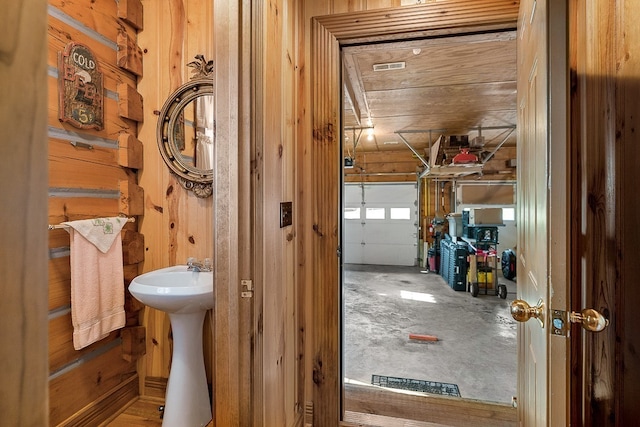 bathroom featuring sink, wooden walls, and concrete flooring