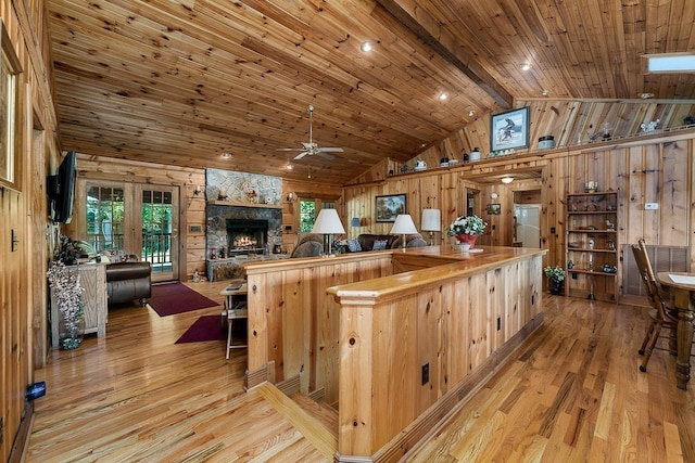 kitchen with vaulted ceiling with beams, wooden ceiling, light hardwood / wood-style flooring, and wooden walls