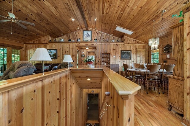 kitchen with wood walls, light hardwood / wood-style floors, ceiling fan, wooden ceiling, and lofted ceiling with skylight