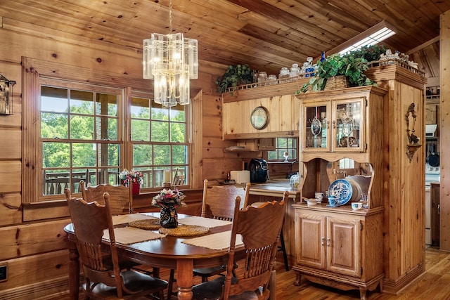 dining room with wood-type flooring, wood ceiling, vaulted ceiling with skylight, wooden walls, and a chandelier