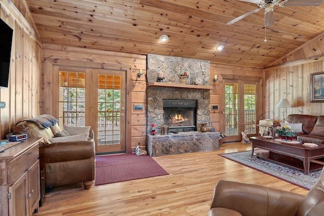 living room featuring lofted ceiling, a stone fireplace, light hardwood / wood-style flooring, wooden ceiling, and ceiling fan