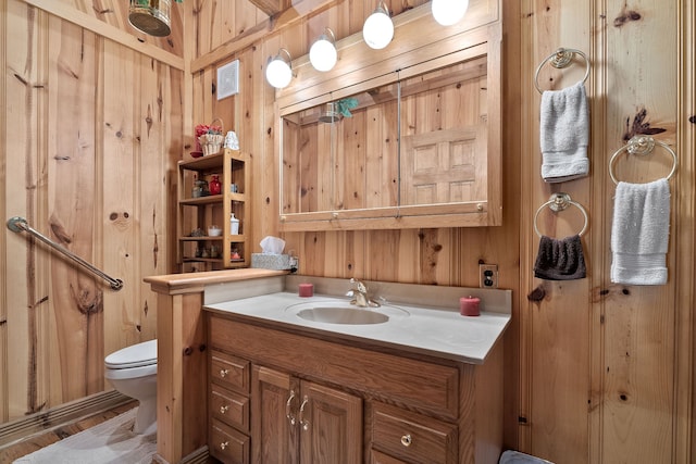 bathroom with vanity, toilet, wood walls, and wood-type flooring