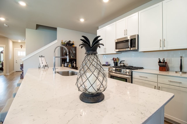 kitchen featuring light stone counters, sink, white cabinetry, appliances with stainless steel finishes, and hardwood / wood-style floors