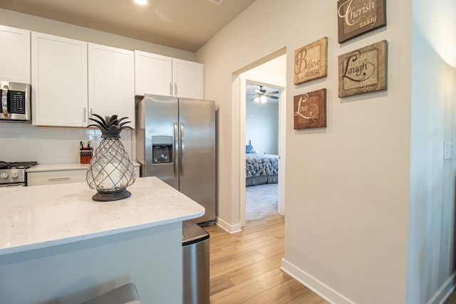 kitchen featuring light stone counters, appliances with stainless steel finishes, light wood-type flooring, and white cabinetry