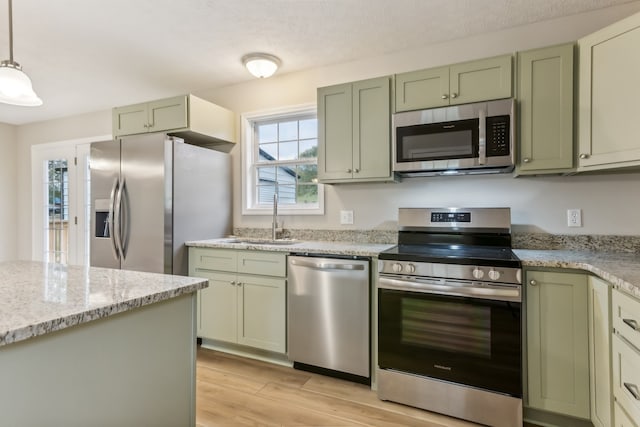 kitchen featuring pendant lighting, stainless steel appliances, green cabinets, and light stone countertops