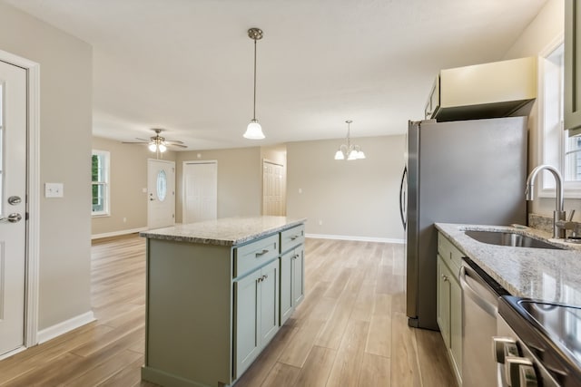 kitchen with light wood-type flooring, hanging light fixtures, appliances with stainless steel finishes, and a center island