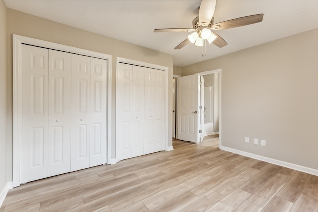 unfurnished bedroom featuring ceiling fan, multiple closets, and light wood-type flooring