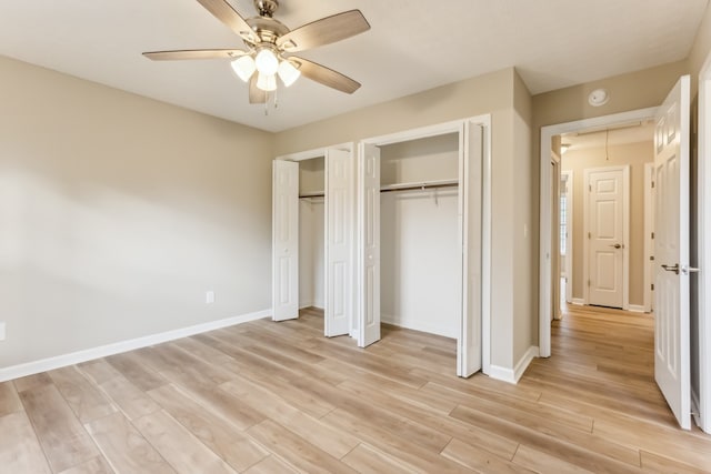 unfurnished bedroom with multiple closets, ceiling fan, and light hardwood / wood-style floors