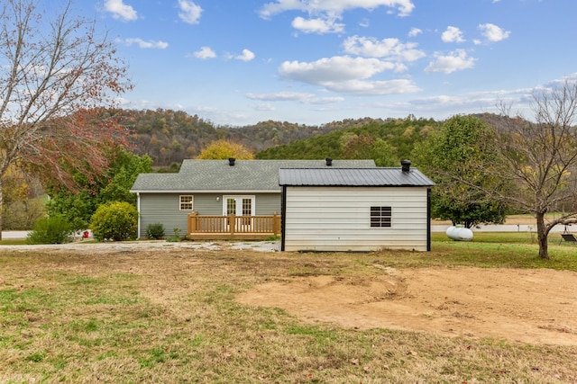 rear view of property with a deck with mountain view and a yard