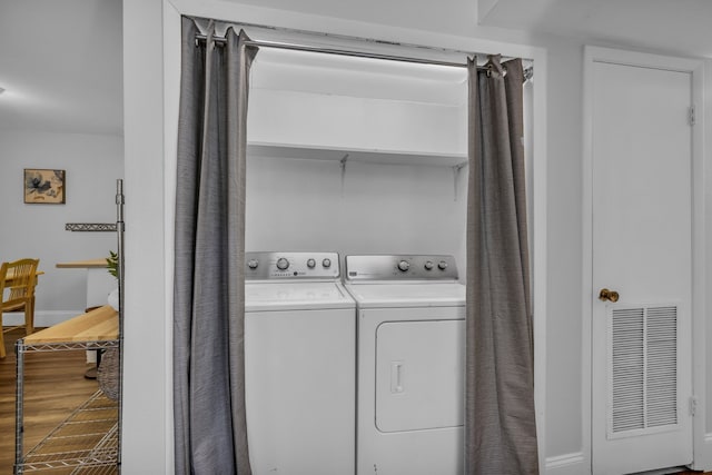 laundry room with washing machine and dryer and wood-type flooring