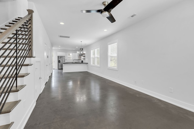 unfurnished living room featuring ceiling fan with notable chandelier