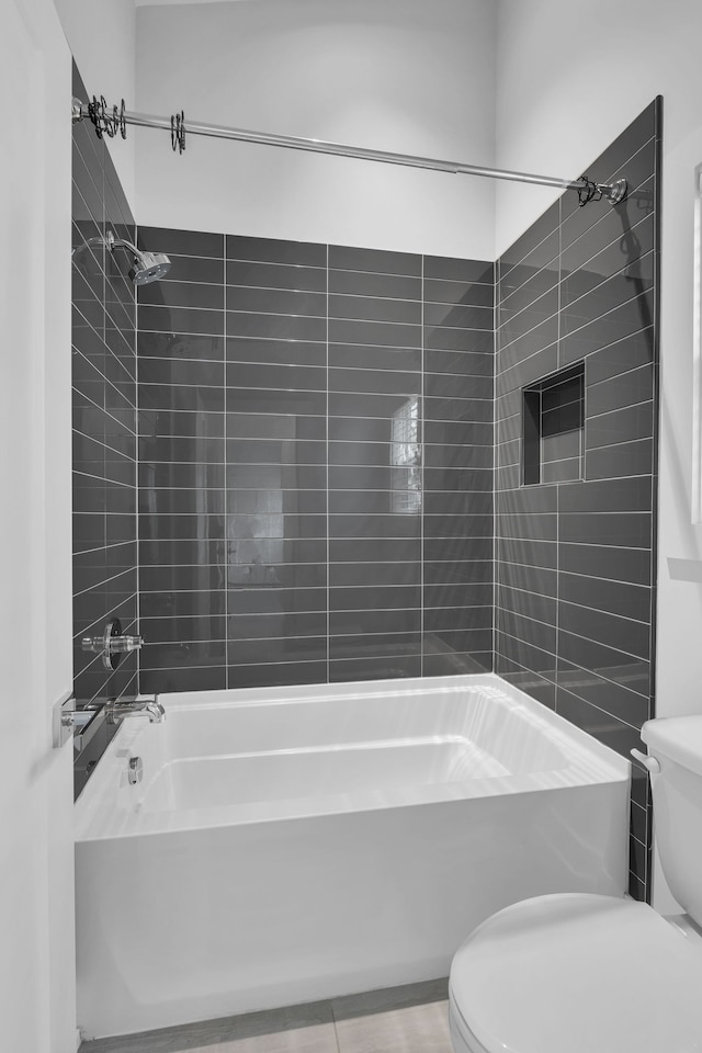 bathroom featuring tile patterned floors, toilet, and tiled shower / bath