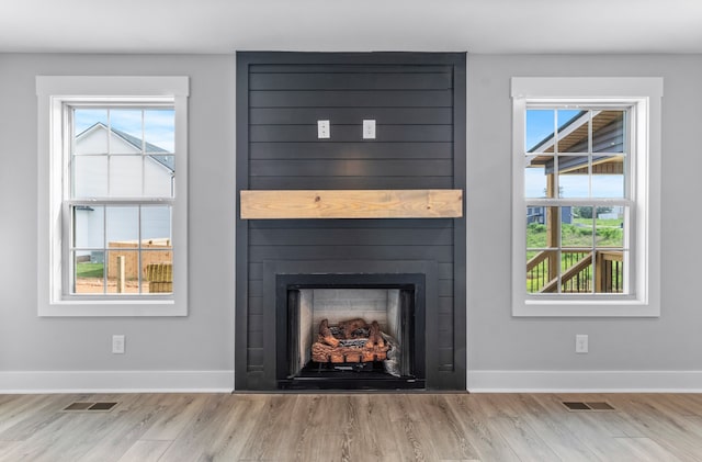 interior details with wood-type flooring and a large fireplace