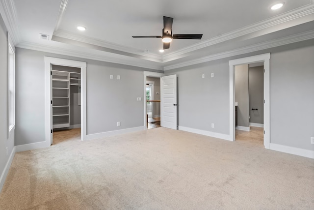 unfurnished bedroom with ceiling fan, a walk in closet, crown molding, and a closet