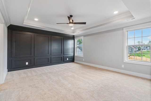 unfurnished bedroom featuring ceiling fan, ornamental molding, a raised ceiling, and light colored carpet