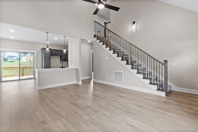 unfurnished living room featuring ceiling fan, sink, and hardwood / wood-style floors