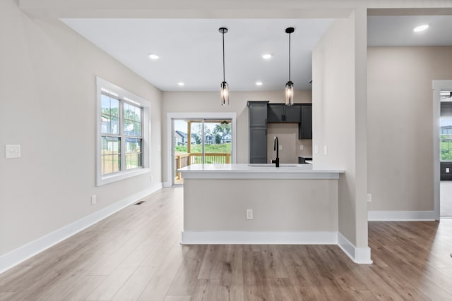 kitchen featuring wood-type flooring, sink, pendant lighting, and kitchen peninsula