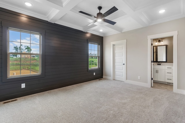 unfurnished bedroom with beamed ceiling, coffered ceiling, connected bathroom, and wood walls