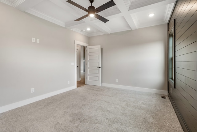 carpeted empty room with beamed ceiling, ceiling fan, coffered ceiling, and crown molding