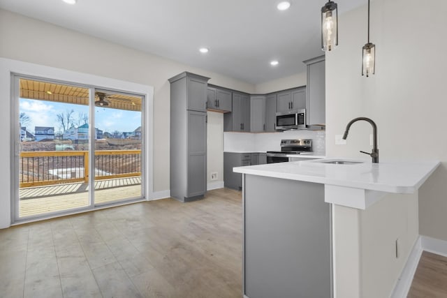 kitchen featuring pendant lighting, sink, gray cabinets, appliances with stainless steel finishes, and kitchen peninsula