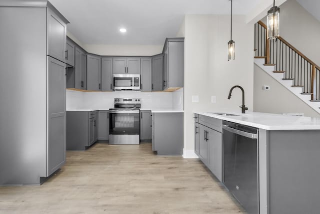 kitchen with gray cabinets, appliances with stainless steel finishes, sink, and decorative light fixtures