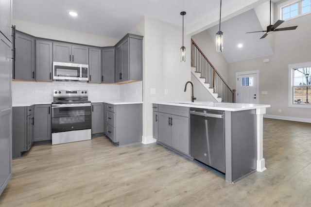 kitchen with gray cabinets, appliances with stainless steel finishes, sink, and backsplash