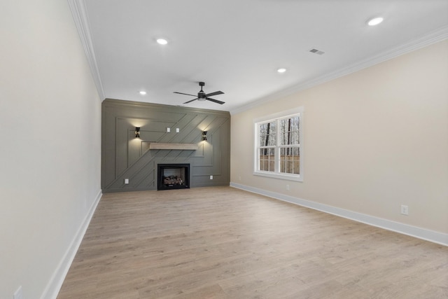 unfurnished living room with ornamental molding, ceiling fan, a fireplace, and light hardwood / wood-style flooring