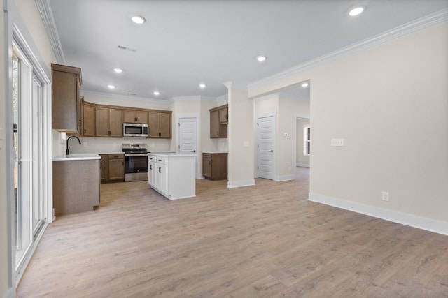 kitchen with ornamental molding, appliances with stainless steel finishes, sink, and light hardwood / wood-style flooring