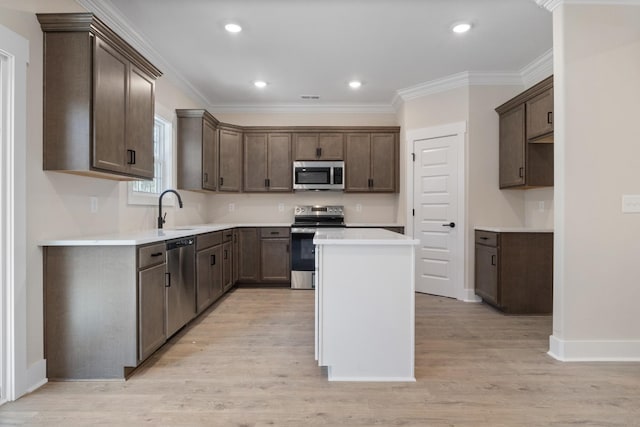 kitchen featuring ornamental molding, appliances with stainless steel finishes, a center island, and sink