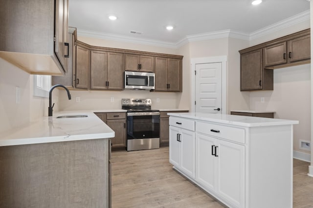 kitchen with stainless steel appliances, ornamental molding, sink, and white cabinets