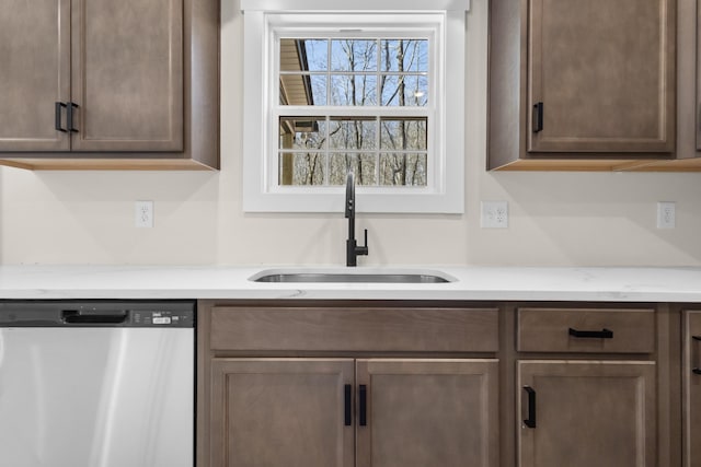 kitchen with light stone counters, stainless steel dishwasher, and sink