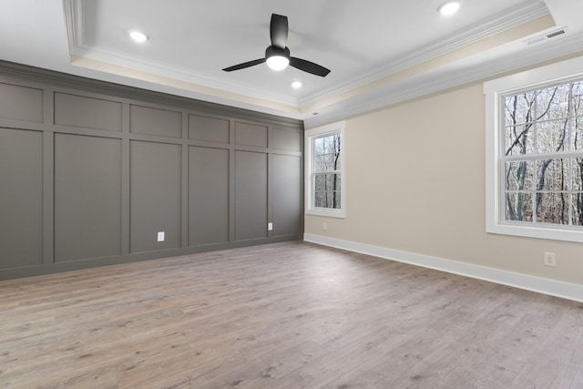 unfurnished bedroom featuring crown molding, a tray ceiling, and light hardwood / wood-style floors