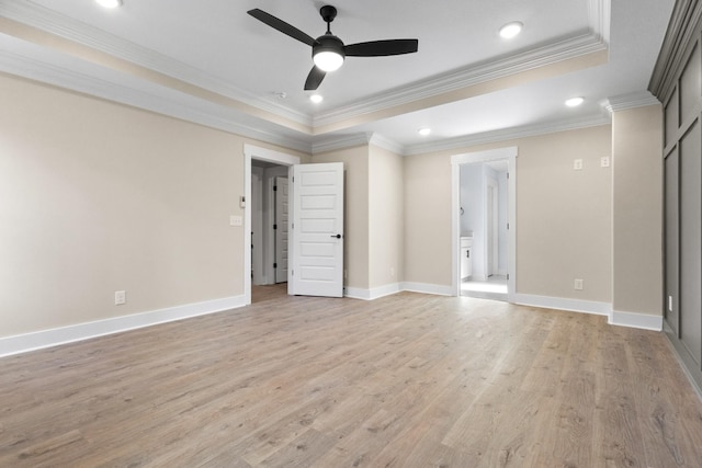 empty room with a raised ceiling, crown molding, ceiling fan, and light hardwood / wood-style flooring