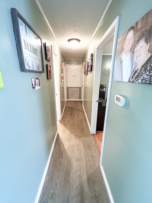 hallway featuring hardwood / wood-style flooring, a textured ceiling, and crown molding