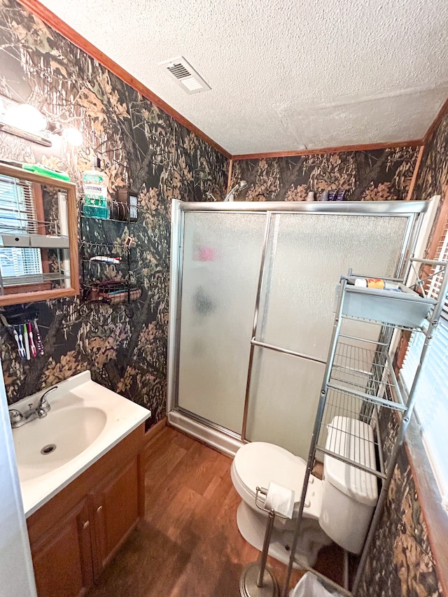 bathroom with a textured ceiling, vanity, toilet, walk in shower, and hardwood / wood-style flooring