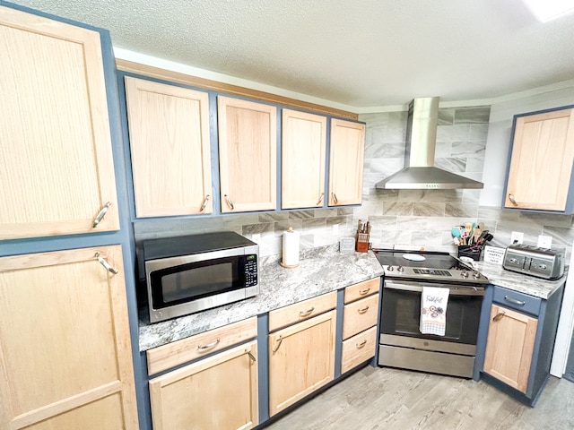 kitchen with wall chimney exhaust hood, backsplash, light brown cabinetry, and stainless steel appliances