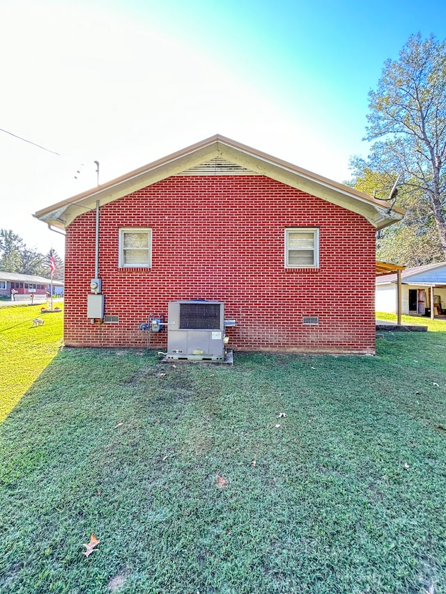 view of side of home with central AC unit and a lawn