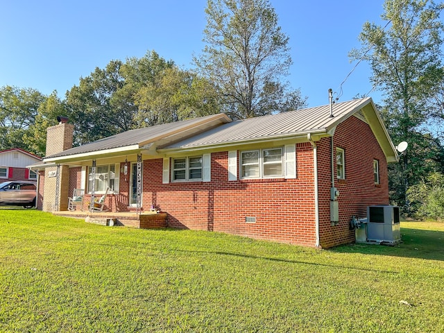 ranch-style home featuring covered porch, central AC unit, and a front lawn