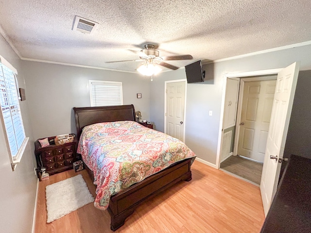 bedroom with ceiling fan, light hardwood / wood-style floors, a textured ceiling, and ornamental molding