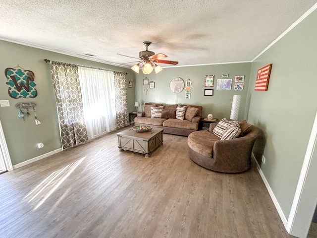 living room with wood-type flooring, a textured ceiling, ceiling fan, and crown molding