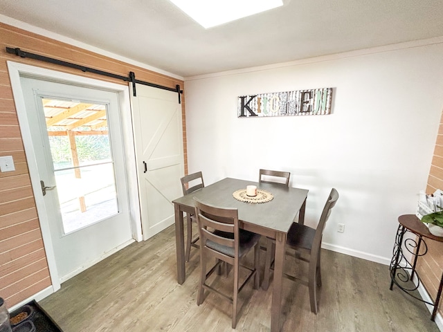 dining room with hardwood / wood-style floors, crown molding, and a barn door