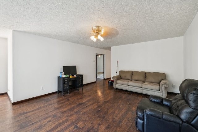 living room featuring ceiling fan, dark wood-type flooring, and a textured ceiling