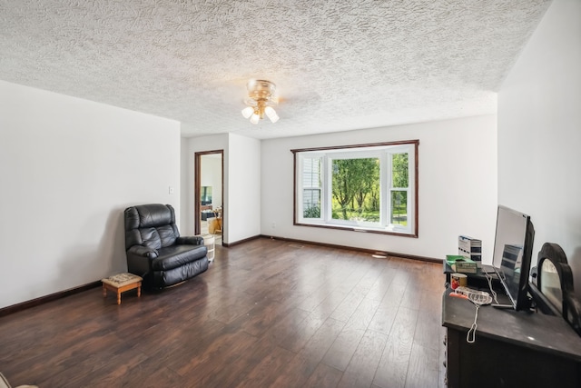 sitting room featuring dark wood-type flooring, ceiling fan, and a textured ceiling