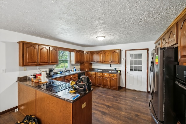 kitchen featuring black appliances, sink, dark hardwood / wood-style floors, and a textured ceiling