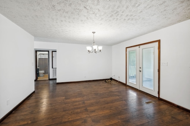 empty room featuring a textured ceiling, french doors, a chandelier, and dark hardwood / wood-style flooring