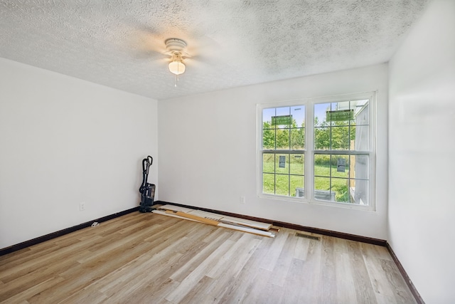 spare room with light wood-type flooring, ceiling fan, and a textured ceiling