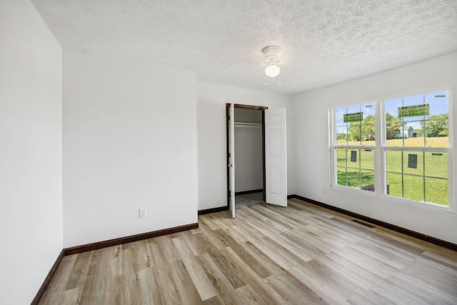 unfurnished bedroom featuring a closet, light wood-type flooring, and a textured ceiling