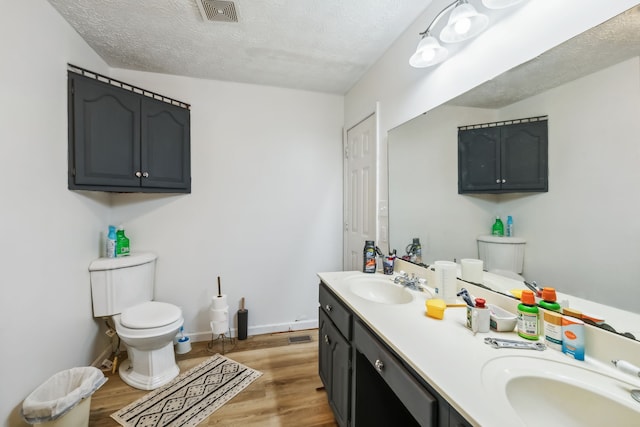 bathroom with vanity, toilet, wood-type flooring, and a textured ceiling