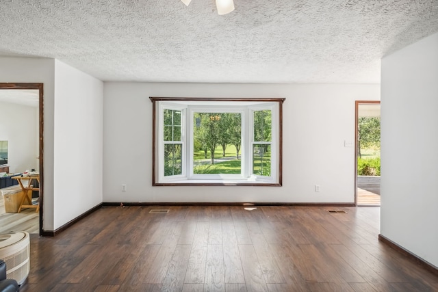 empty room featuring a textured ceiling and dark wood-type flooring