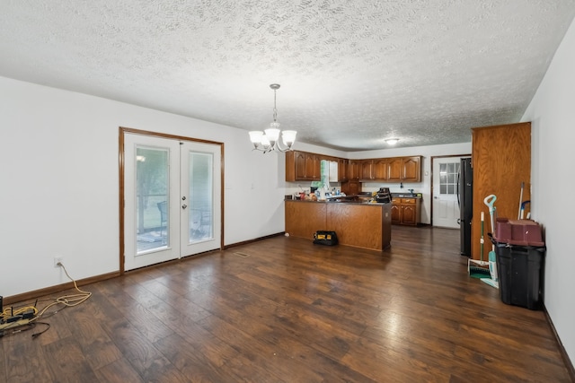 kitchen with dark hardwood / wood-style floors, kitchen peninsula, fridge, hanging light fixtures, and a textured ceiling